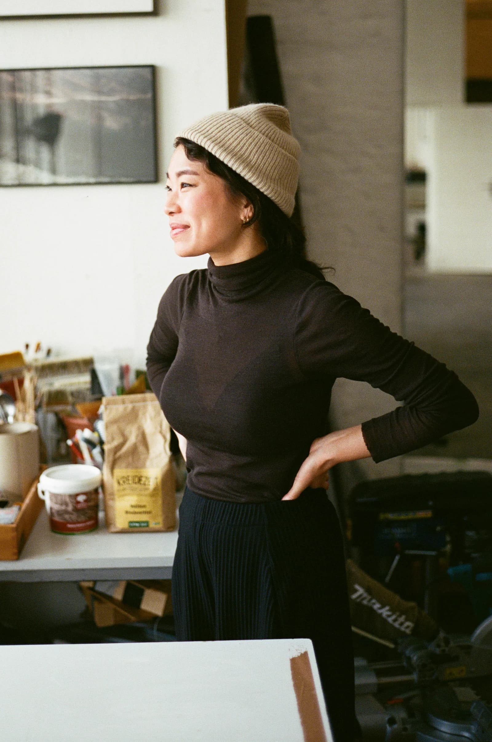 Jeewi Lee in her studio, wearing a cream beanie and dark turtleneck