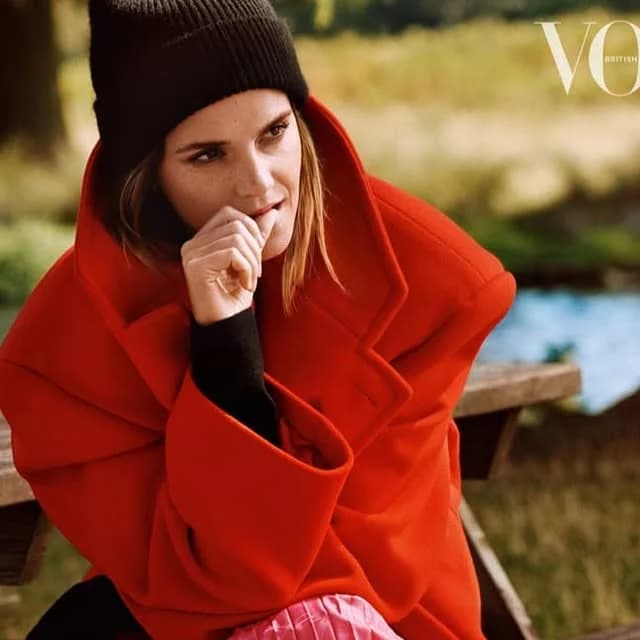Emma Watson met een zwarte beanie en rode jas in de coverstyling van British Vogue van december 2019
