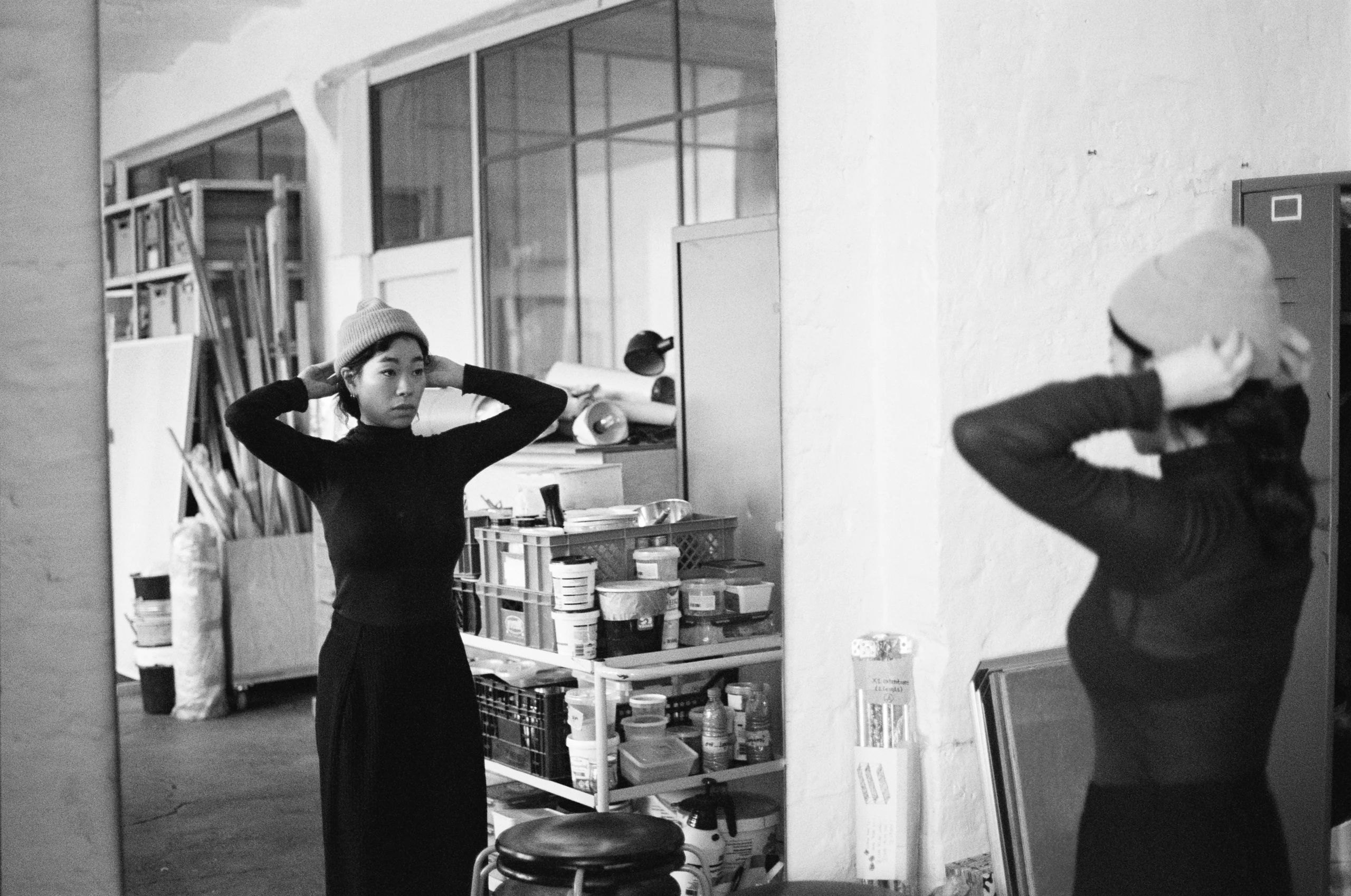 Jeewi Lee weerspiegeld in de spiegel van haar atelier op een zwart-witfoto