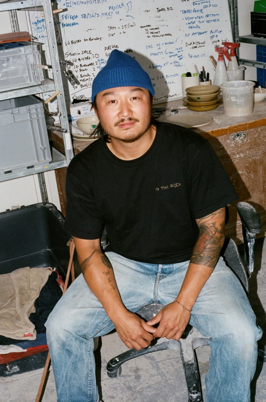 Johannes Tsang seated in his ceramics studio, wearing a blue beanie