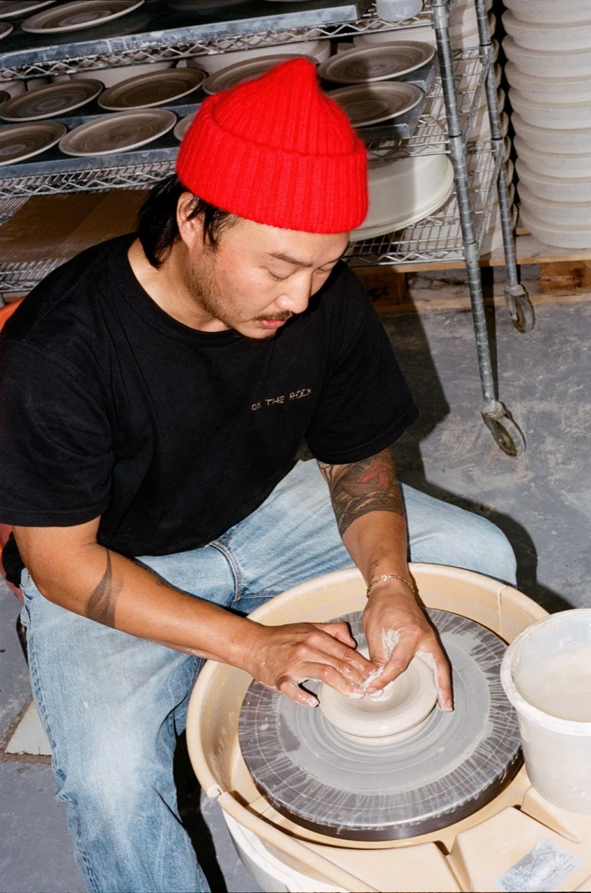 Johannes shaping a bowl on the pottery wheel, wearing a red beanie