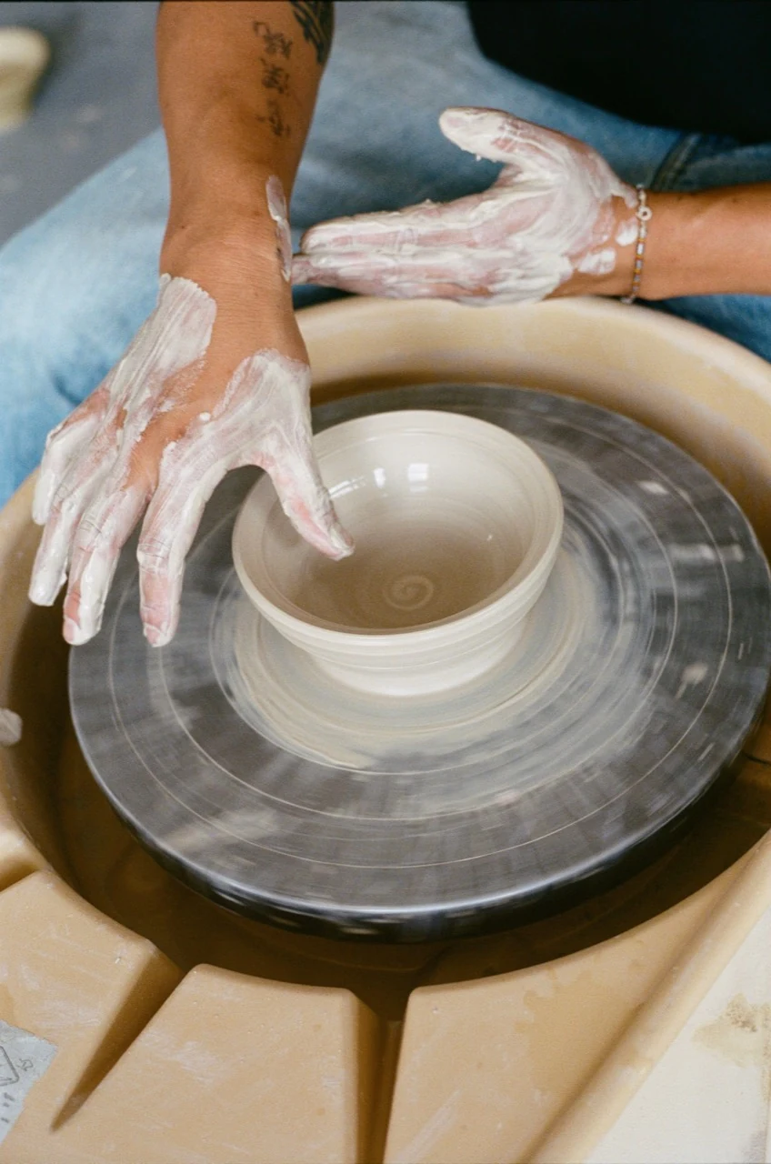 Johannes’s clay-covered hands shaping a bowl on the wheel