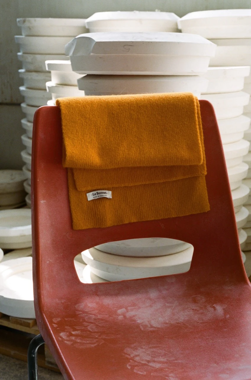 An Orange Peel Le Bonnet scarf on a red studio chair beside plaster moulds