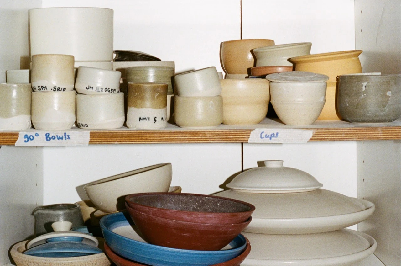 Glazed bowls, cups and plates on the studio shelves